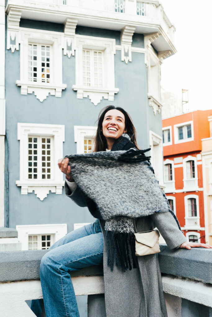 Mujer modelo sonriendo con bufanda en la ciudad